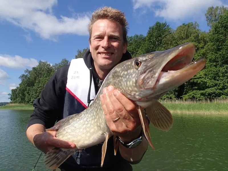 An angler holding a pike on the summer sea